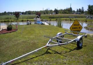 A trailer with a sign on its rear and near a pond